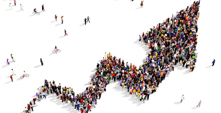 A large crowd of people is arranged to form the shape of an upward-trending arrow, visually representing growth and trend analysis in descriptive analytics.